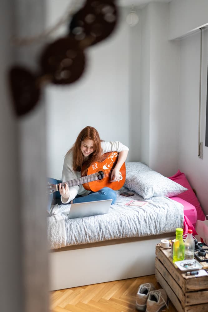 A roomie playing guitar in her own room