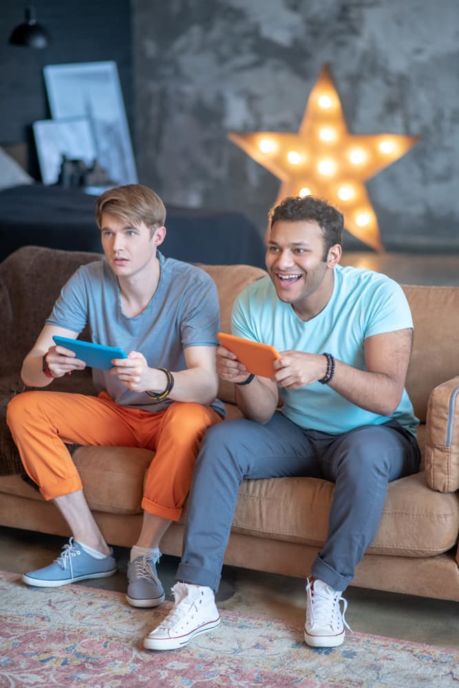 Two roomies playing video games together in the living room