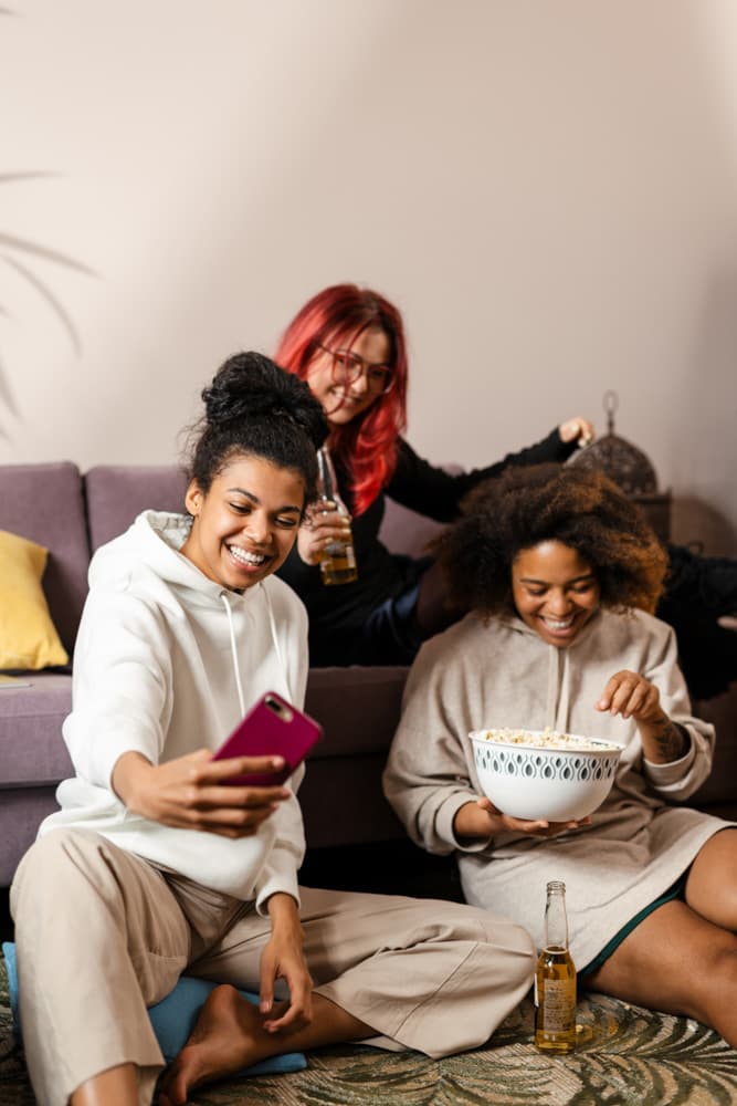 Three roomies relaxing in the living room, taking a selfie and sharing popcorn